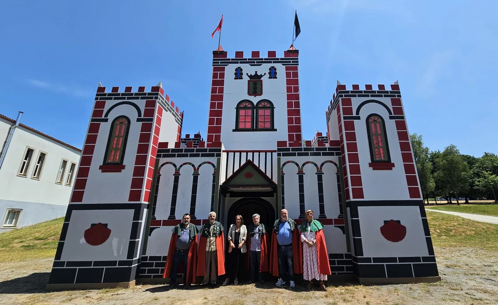 阿爾蘇阿 San Xoán 慶典的木造城堡 Castelo de Santa María，前方站著身穿紅披風的兄弟會成員