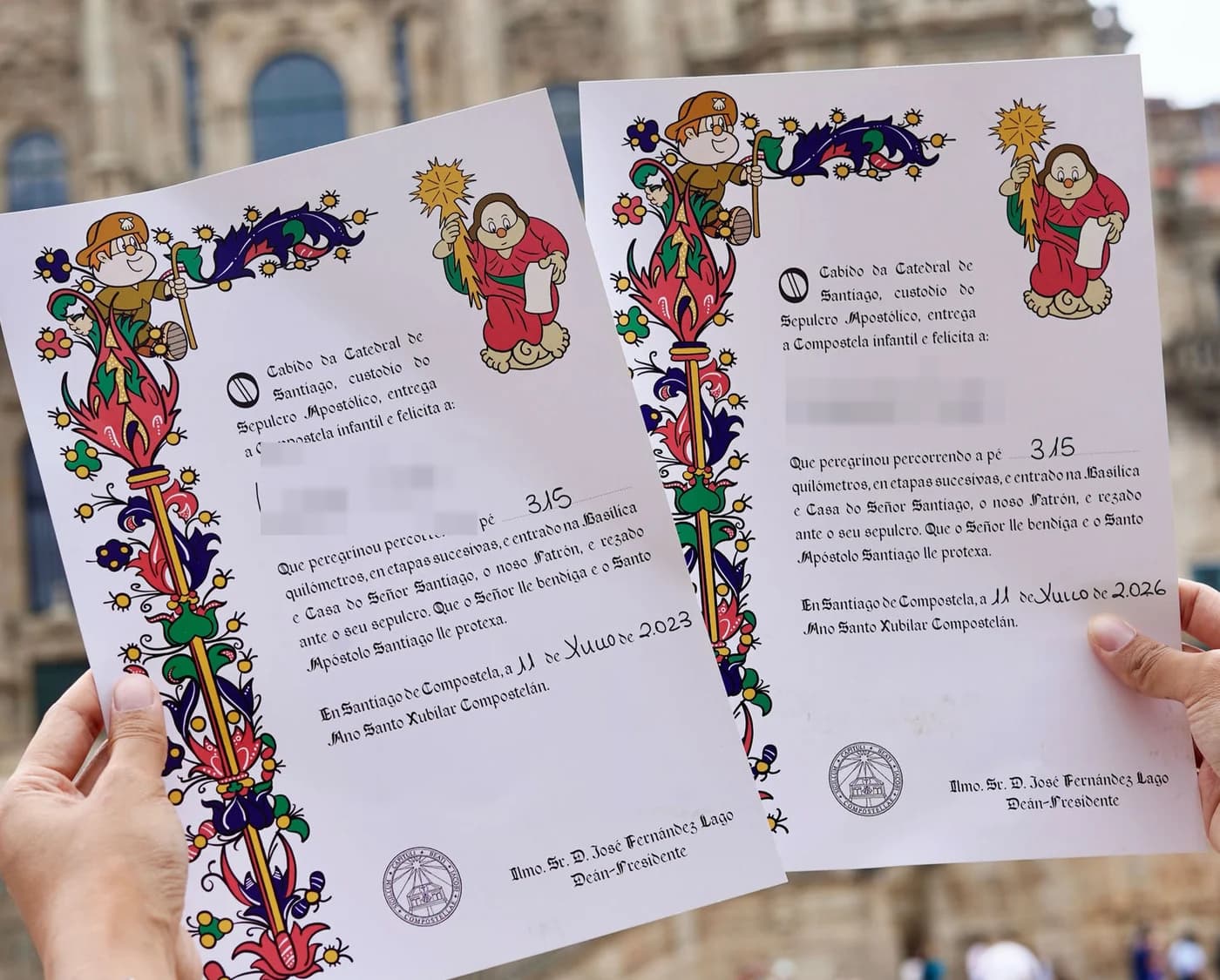 兩張兒童版 Compostela 證書，在聖地亞哥主教座堂前展開；孩子的名字已遮去